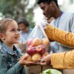 Child receiving a bag of fresh food from charity volunteers